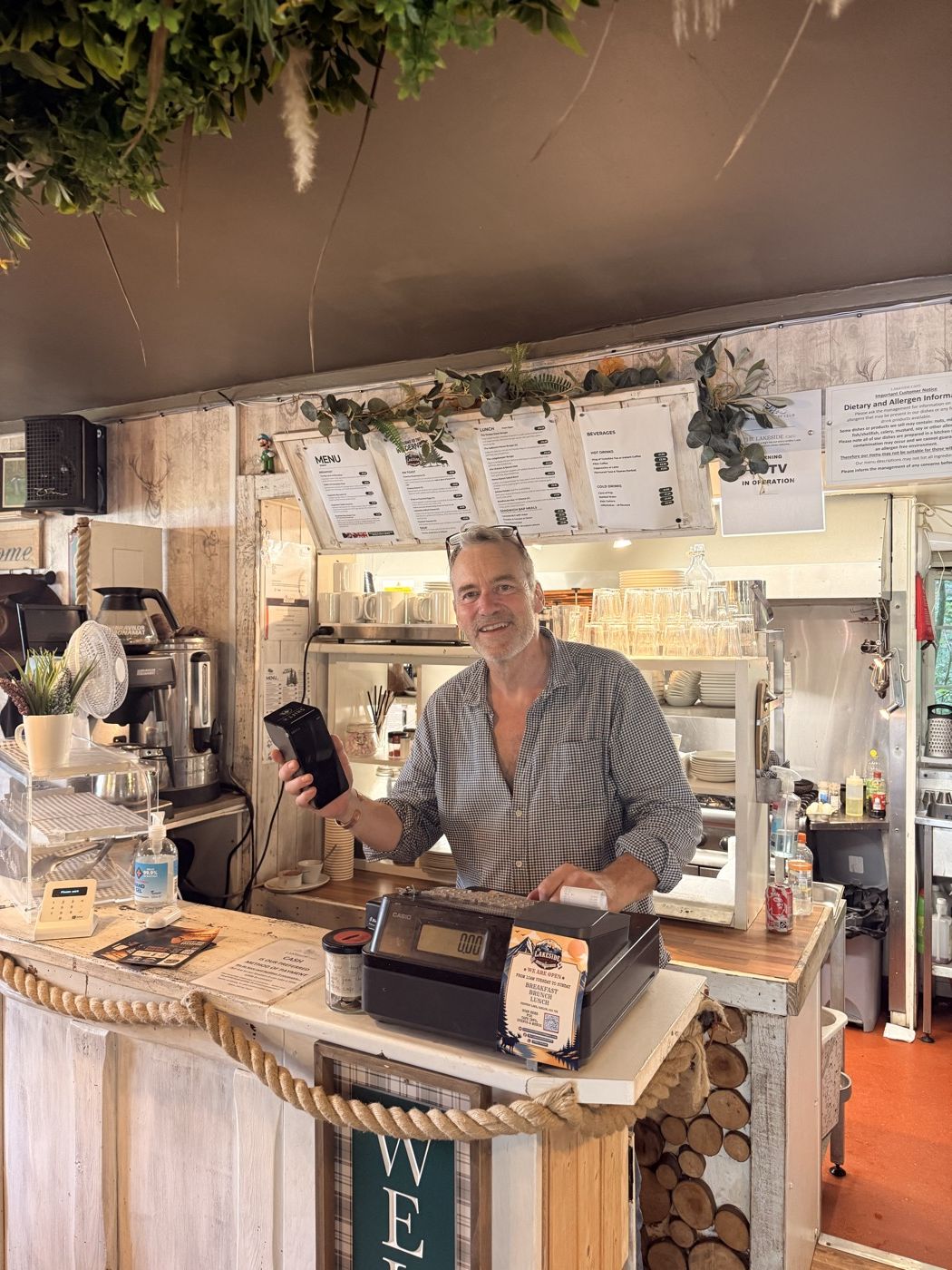 The owner of The Lakeside Café holding a card terminal at the counter