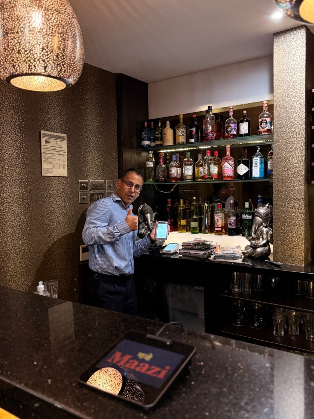 The owner of Maazi Indian Restaurant at the bar with his Square reader